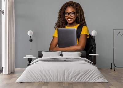 Friendly african woman high school student typing on portable computer isolated on gray background Wall mural